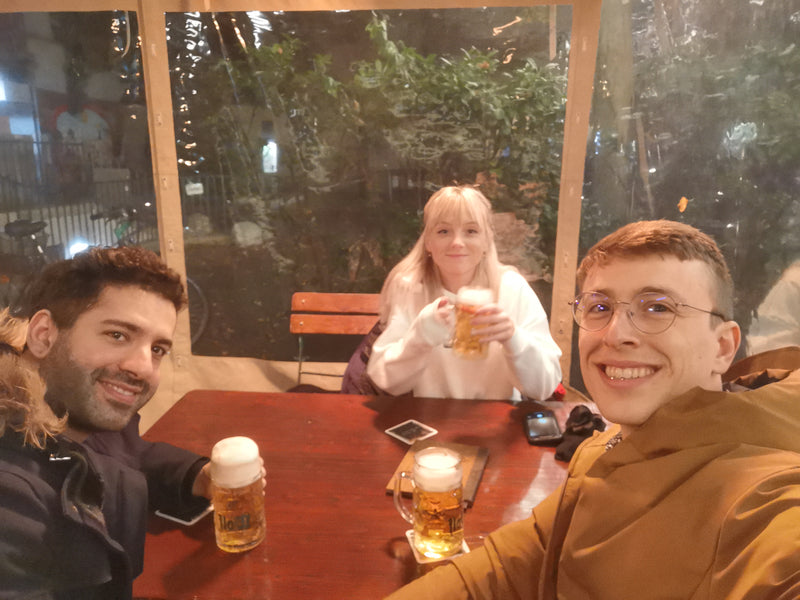 Two people sitting at a table with drinks, smiling at the camera.