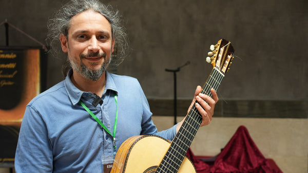 Man holding a classical guitar in an indoor setting