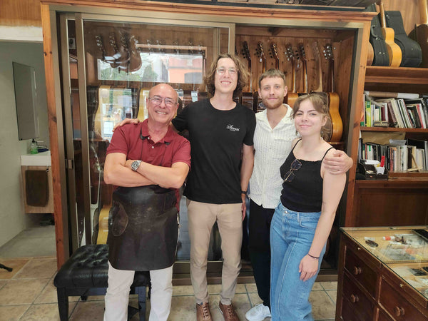 Four people posing together in a guitar store.
