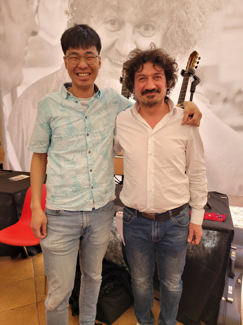 Two people standing together with a guitar in an indoor setting