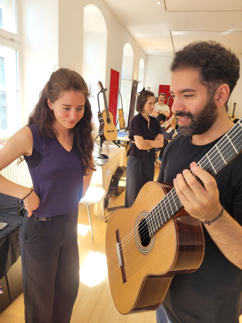 Two people playing classical guitars in a bright indoor setting