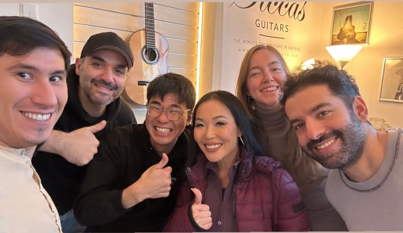 Group of six people posing together in a room with musical instruments.